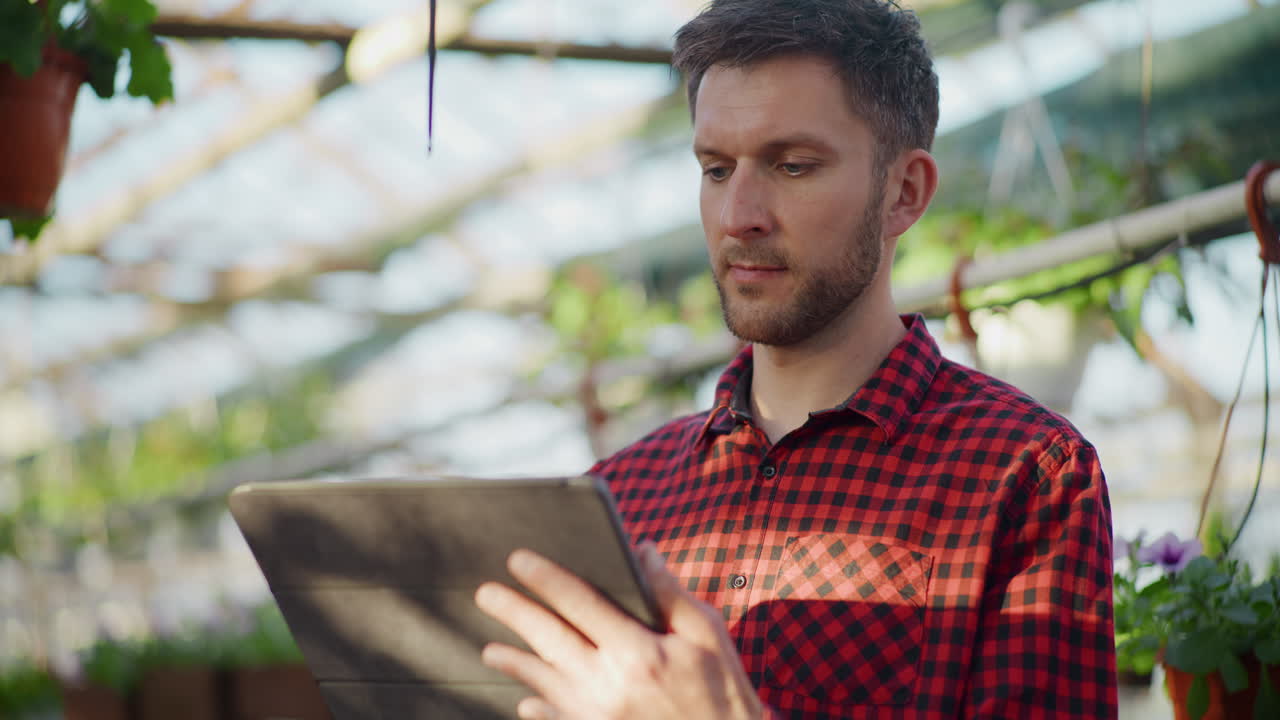 Gardener Using Digital Tablet in Greenhouse