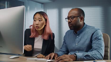 Two professionals engage in a focused work session at a sleek desk in a contemporary office, collaborating on a project with intense concentration and teamwork.