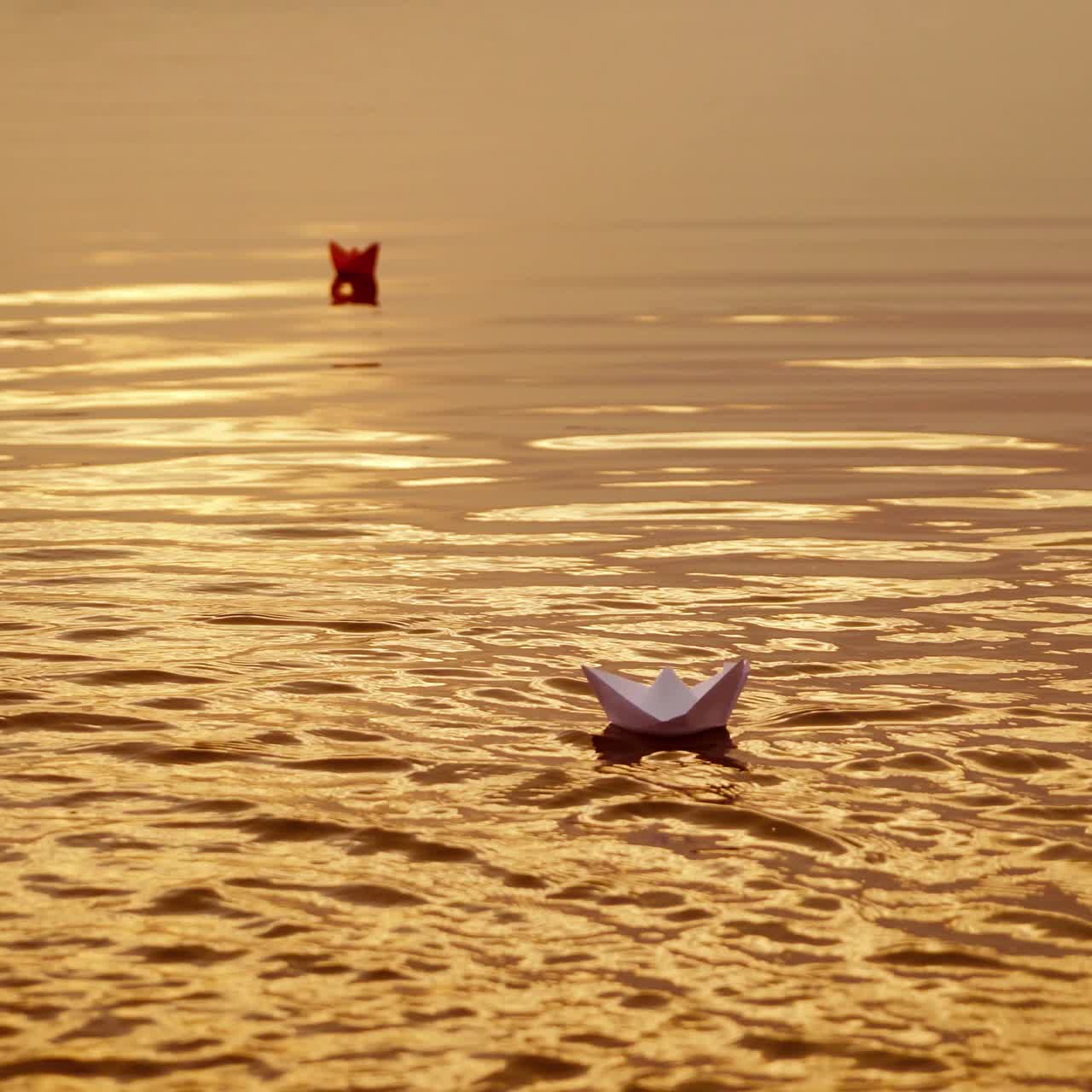 Floating paper boats on the water at sunset. Paper boat. Origami.