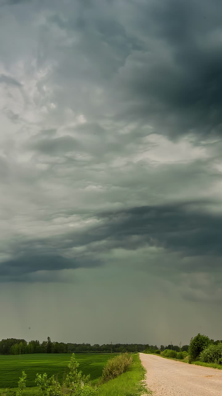 Grå stormskyer over en grusvej og mark - Timelapse, vertikalt skud.