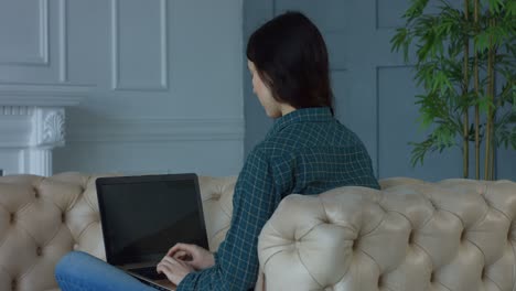 mujer encantadora en red en la computadora portátil en casa