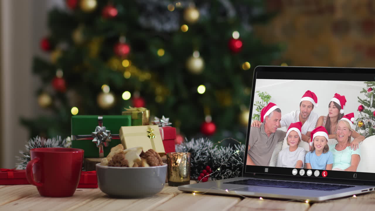 familia feliz usando sombreros snata en videollamada en computadora portátil, con decoraciones de navidad y árbol