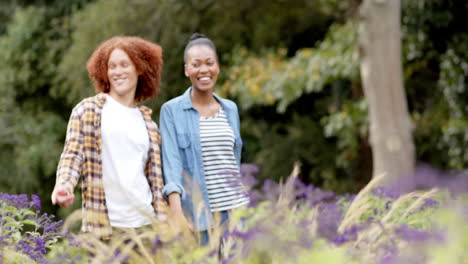 Happy-diverse-couple-holding-hands-walking-and-talking-in-garden,-slow-motion