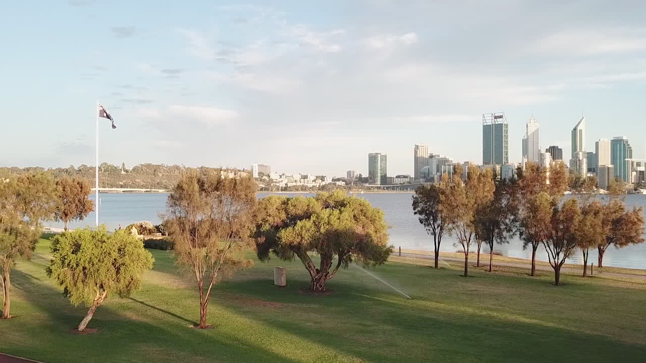 asta de bandera australiana en el parque, pedestal aéreo para revelar la ciudad en la distancia