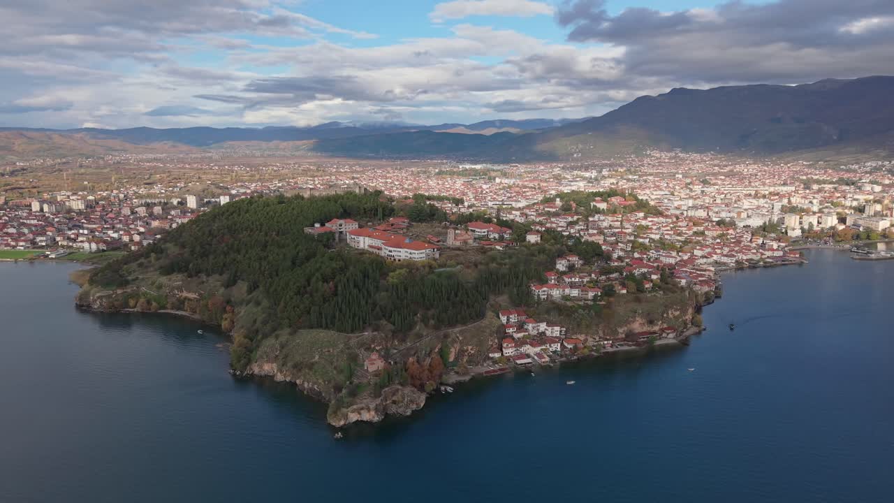 A sweeping aerial panorama of Ohrid, featuring the historic Old Town monuments and Samuel's Fortress, overlooking the crystal-clear expanse of Lake Ohrid under a bright sun