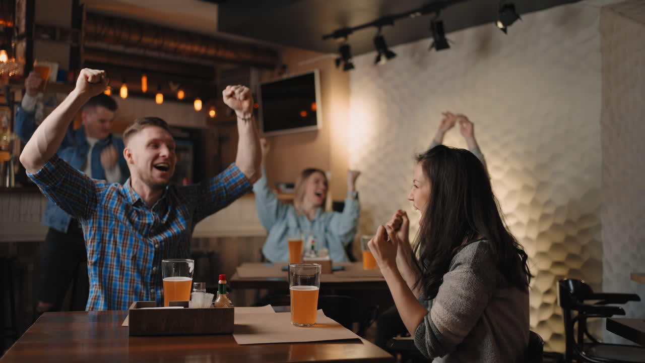 amigos están viendo juntos emocionalmente viendo fútbol en la televisión en un bar y celebrando la victoria de su equipo después de anotar un gol. ver baloncesto. el disco anotado. aficionados en el pub