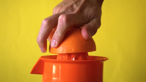 Hand squeezing an orange in manual juicer