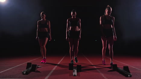 corredoras en la pista de atletismo agachadas en los bloques de salida antes de una carrera. en cámara lenta.
