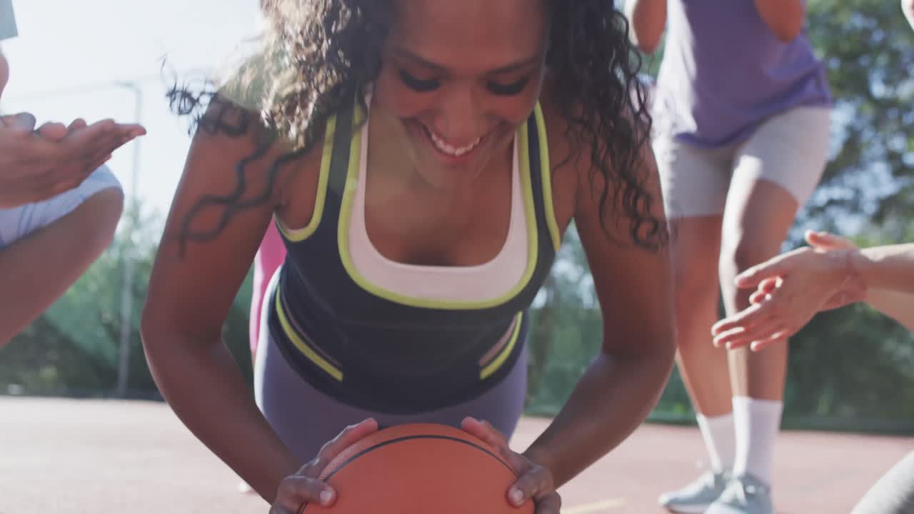 Happy diverse female basketball team training on sunny court, in slow motion