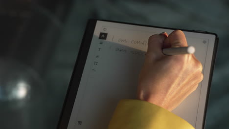 donna che scrive affermazioni positive su un quaderno digitale su tablet: concetto motivazionale di salute mentale, potente self-talk per aumentare la fiducia in se stessi e aumentare l'autostima, sono sicuro, di successo