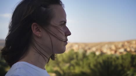mujer joven que parece pensativa mientras se para en el viento afuera