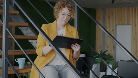 woman working on tablet on stairs in office