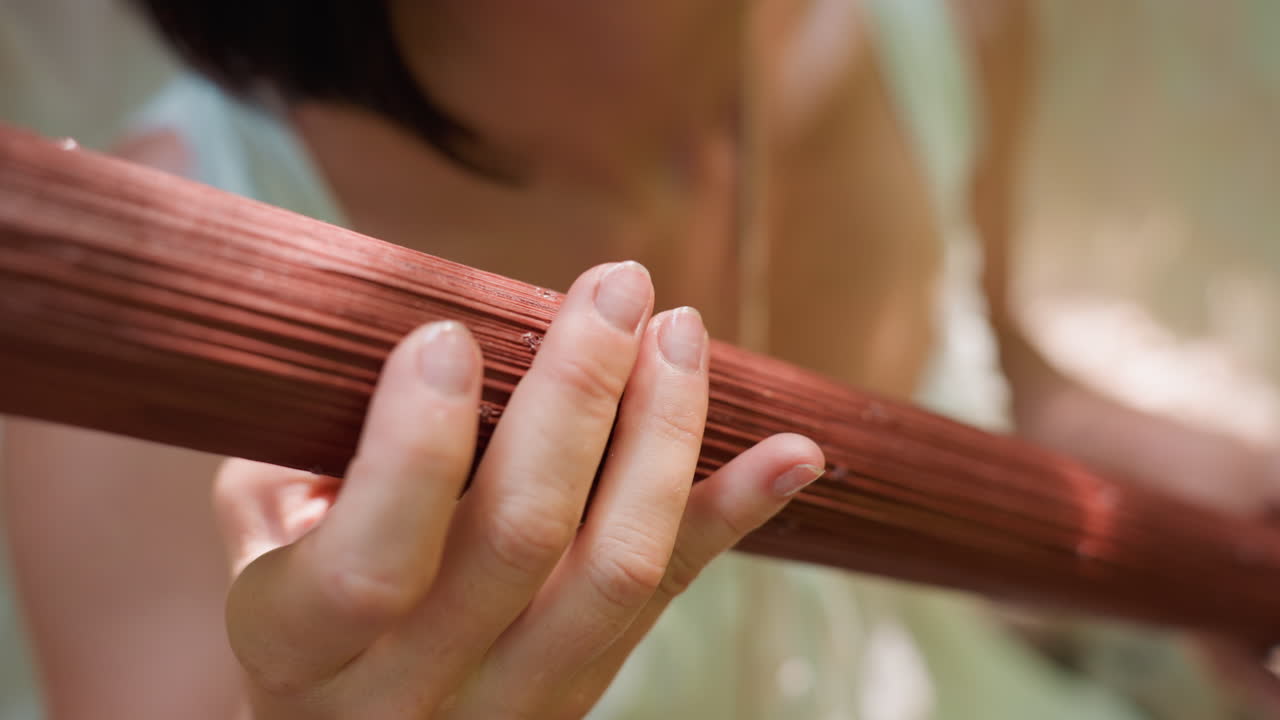 Extreme close up of forest guardian gently rotating wooden staff wrapped with rope under sunlight, focus on hand movement and texture, expressing harmony