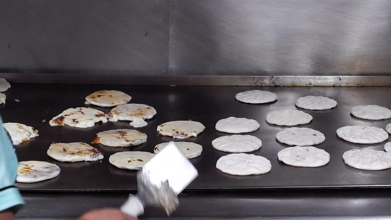 las pupusas chisporrotean mientras se fríen en una parrilla enorme en el restaurante de el salvador