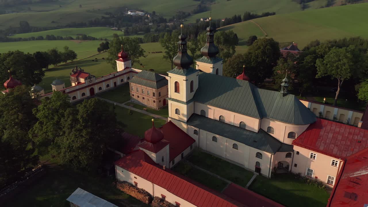 снимок чешской сельской местности с монастырем на вершине холма во время заката