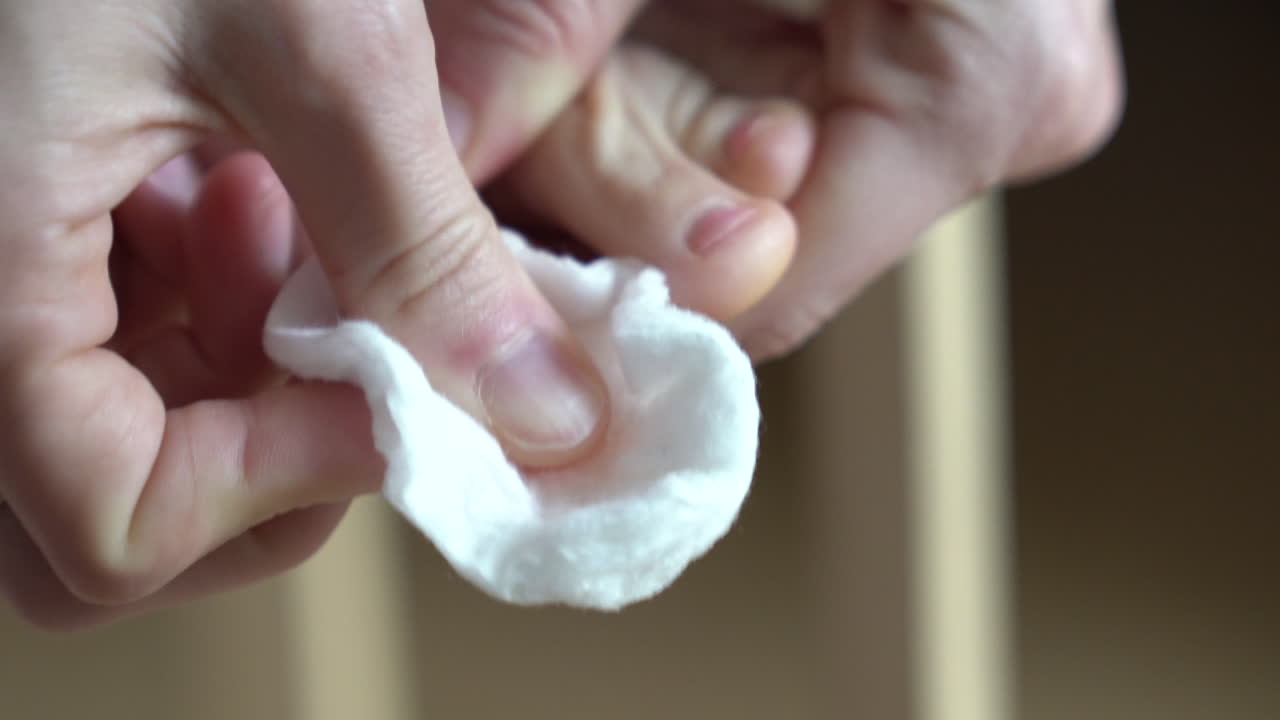 mujer quitando pintura de uñas rosa de los dedos de los pies, limpiando suavemente