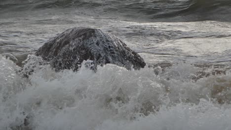 Waves-in-the-sea-during-a-thunderstorm-at-sunset,-large-stones-on-the-sea-shore