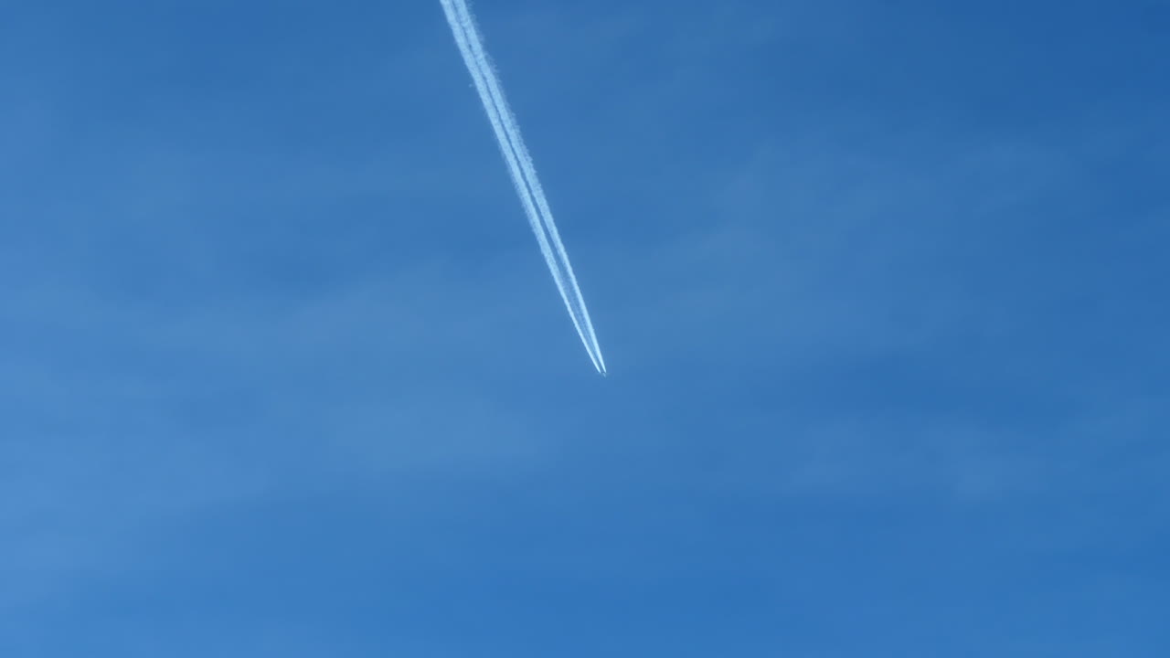 푸른 하늘에 하얀 비행운을 남기고 비행 중인 비행기의 먼 전망