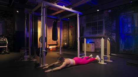 Fit trainer doing lumbar exercises lying face down alone in the gym
