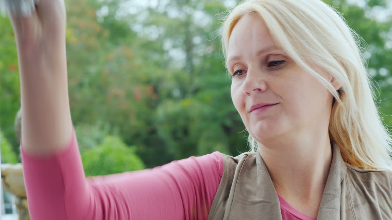 uma mulher esfrega uma janela em um café ou uma pequena loja vista de dentro da sala