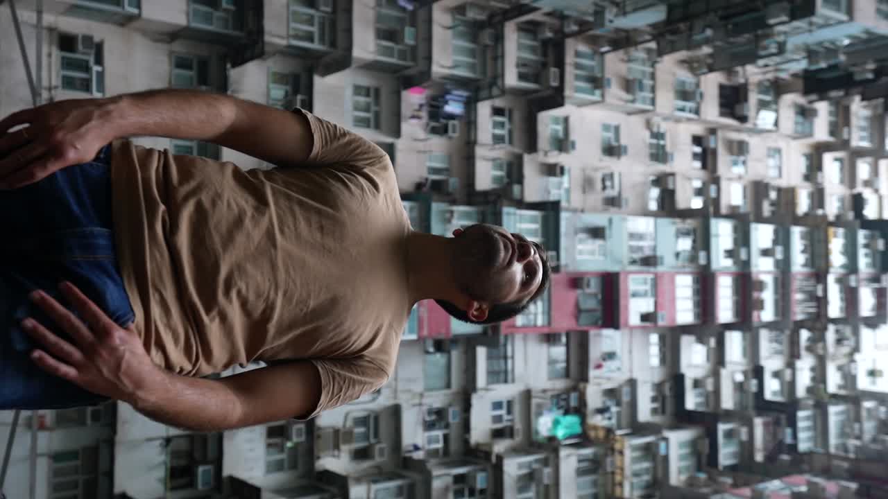 Man gazes at the towering Yick Cheong Building in Hong Kong from a low angle shot. Vertical