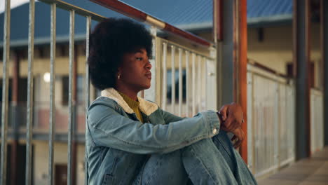 a pensive woman in denim sitting outdoors