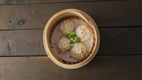 composición de vapor de bambú con dumplings de dim sum sobre un fondo de madera