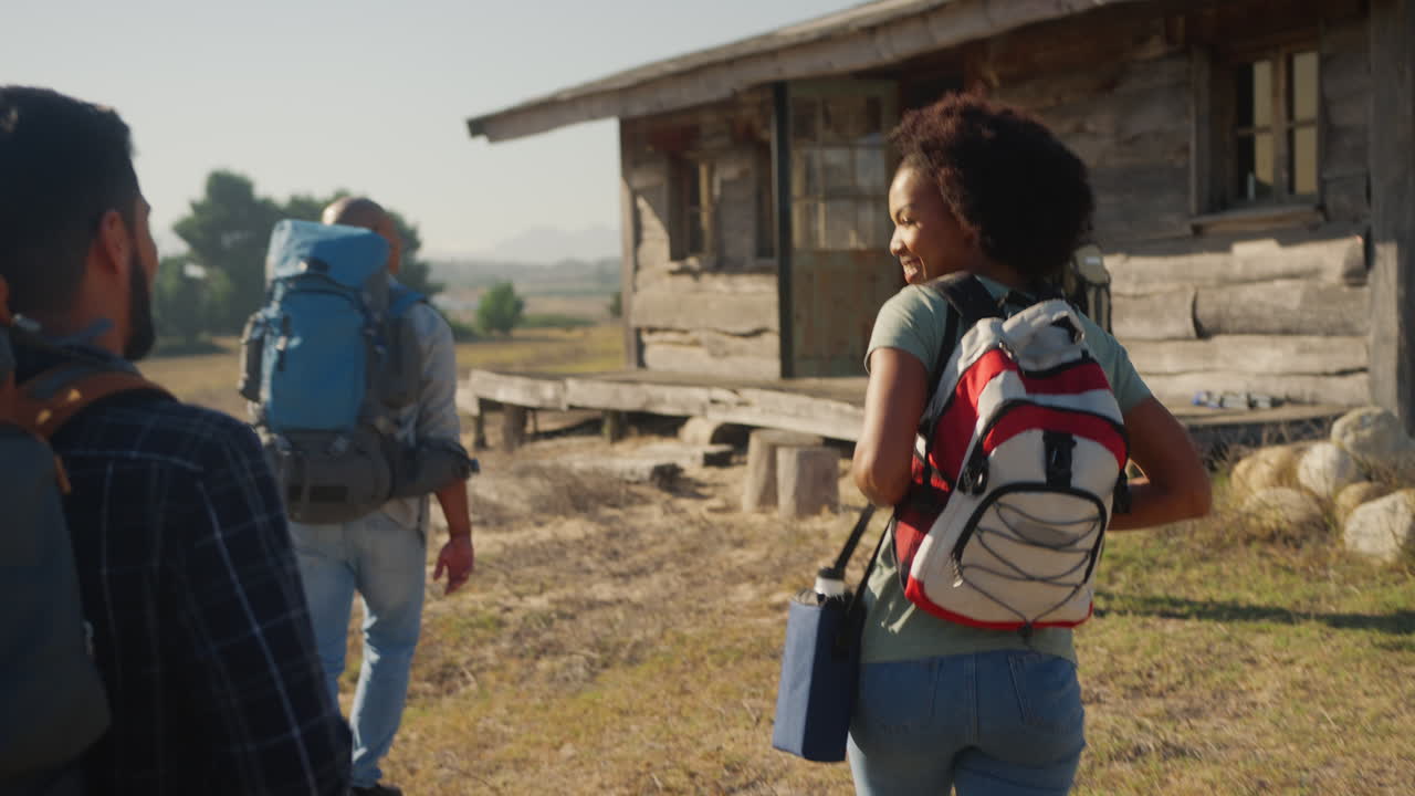 vista trasera de un grupo de amigos con mochilas caminando juntos en el campo