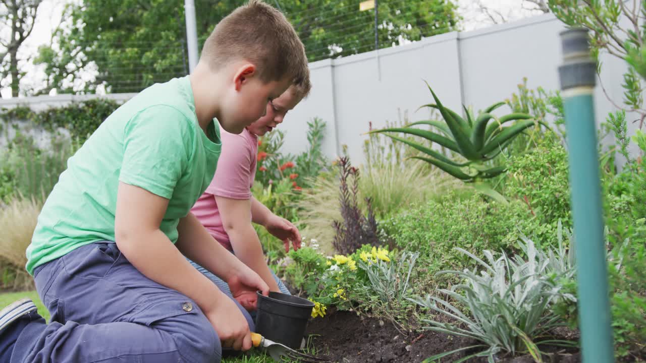 feliz niño caucásico con su hermano jardinería juntos en el jardín
