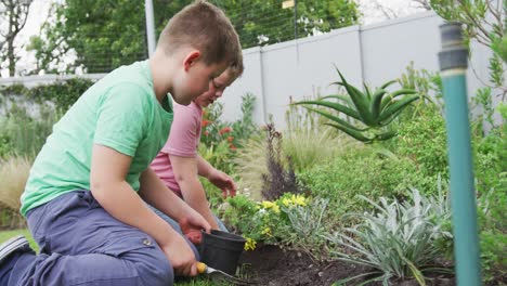 Glücklicher-Kaukasischer-Junge-Mit-Seinem-Bruder,-Der-Gemeinsam-Im-Garten-Gärtnert