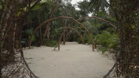 Movimiento-De-Drones-Hacia-Atrás-De-Una-Cabaña-Natural-En-Una-Playa-Entre-Palmeras-En-La-Selva