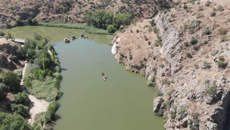 drone overflying a green looking tajo river in toledo, spain