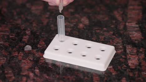 squeezing droplets of solution into a covid-19 rapid antigen test tube