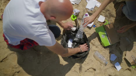 top view of couple picking garbage on beach