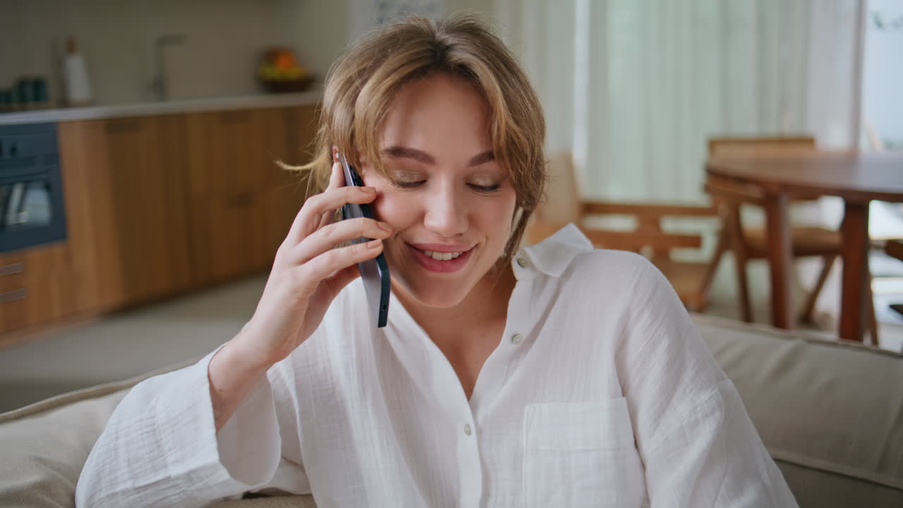 Joyful woman speaking cellphone holding apple at home couch closeup. Happy lady