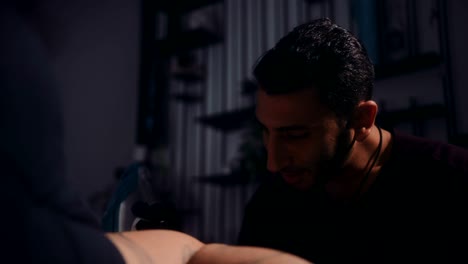 tatuador feliz trabajando en el tatuaje del cliente en un taller profesional
