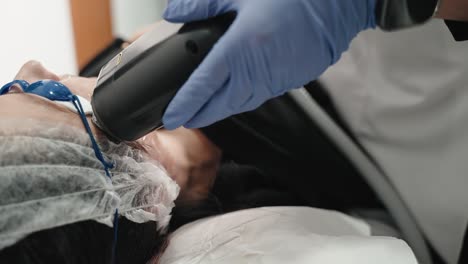 professional using laser device on woman's face during a skincare treatment session