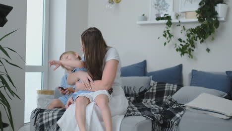 mamá en un vestido sentada en un diván abrazando a su hijo