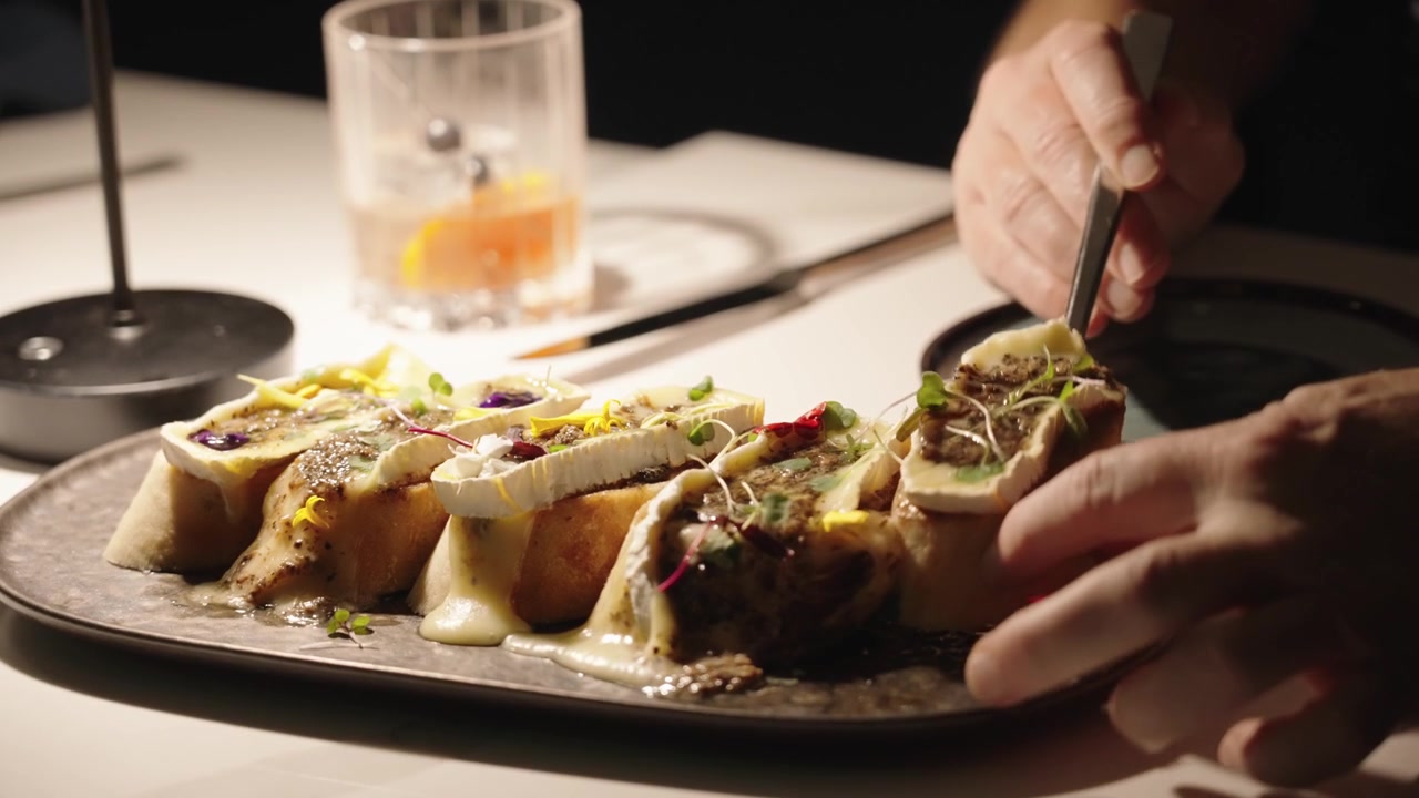 4K footage of a happy couple sharing an elegant appetizer with red wine at a refined hotel restaurant, capturing upscale dining, fine cuisine, and intimate lifestyle atmosphere.