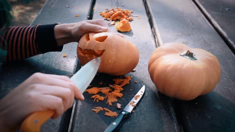 mujer tallando calabazas para halloween en mesa de madera