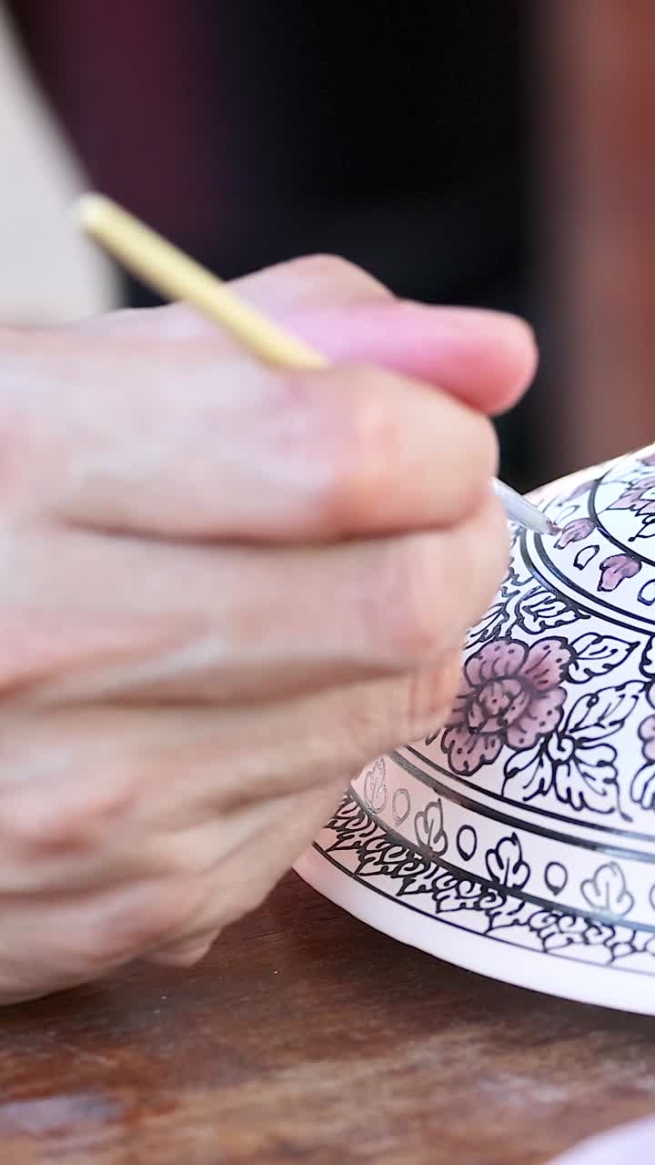 아티스트가 전통적인 태국 세라 그에 복잡한 패턴을 조심스럽게 그립니다.