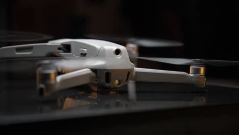video cinematográfico de un dron encendido iluminado con una luz suave desde arriba y luces naranjas en el fondo, filmado en 4k con movimiento de cámara