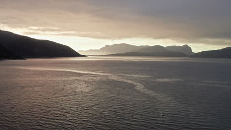 노르웨이의 소그네피오르드 (sognefjord) 를 오르면서 멀리 떨어진 그림자 산과 섬 위에서 해가 지는 쪽으로 이동하는 공중 사진