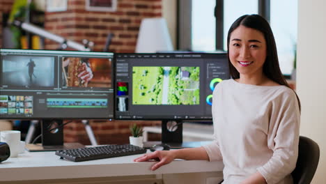 Asian-woman-video-editor-working-with-dual-monitors-in-living-room