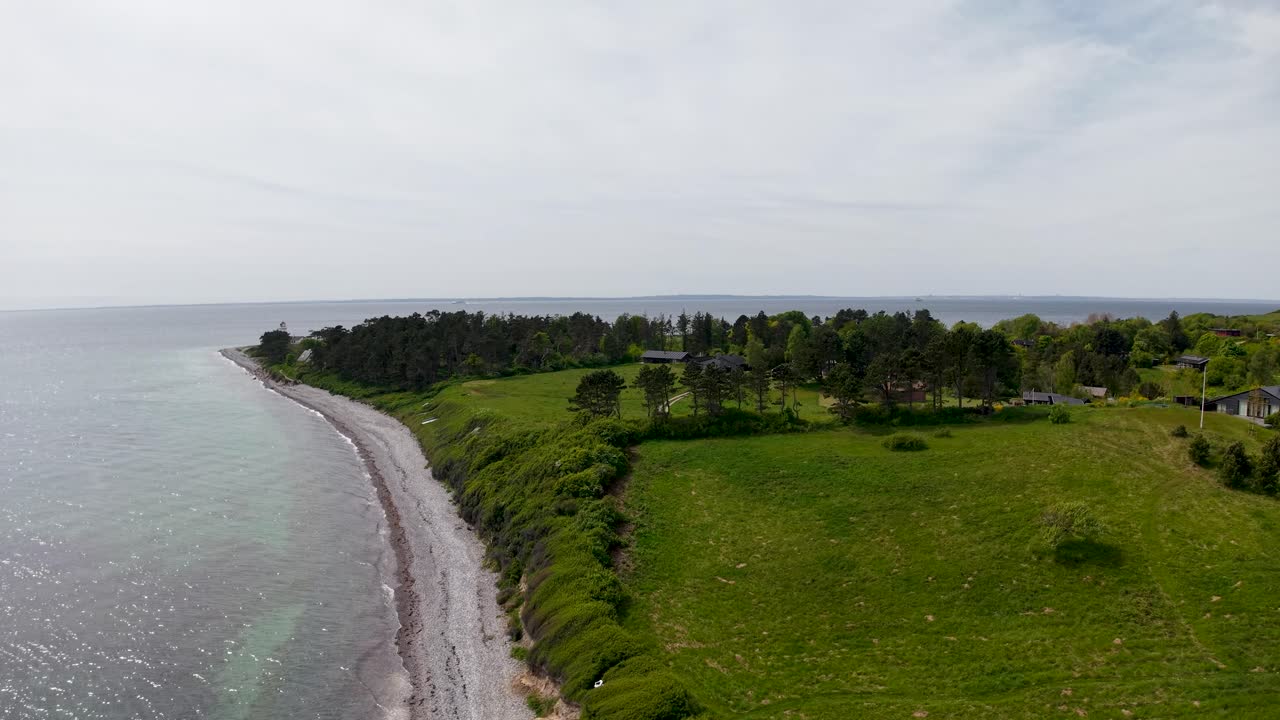 Drone aerial footage featuring a Danish coastline with sandy beach and lush green countryside stretching inland
