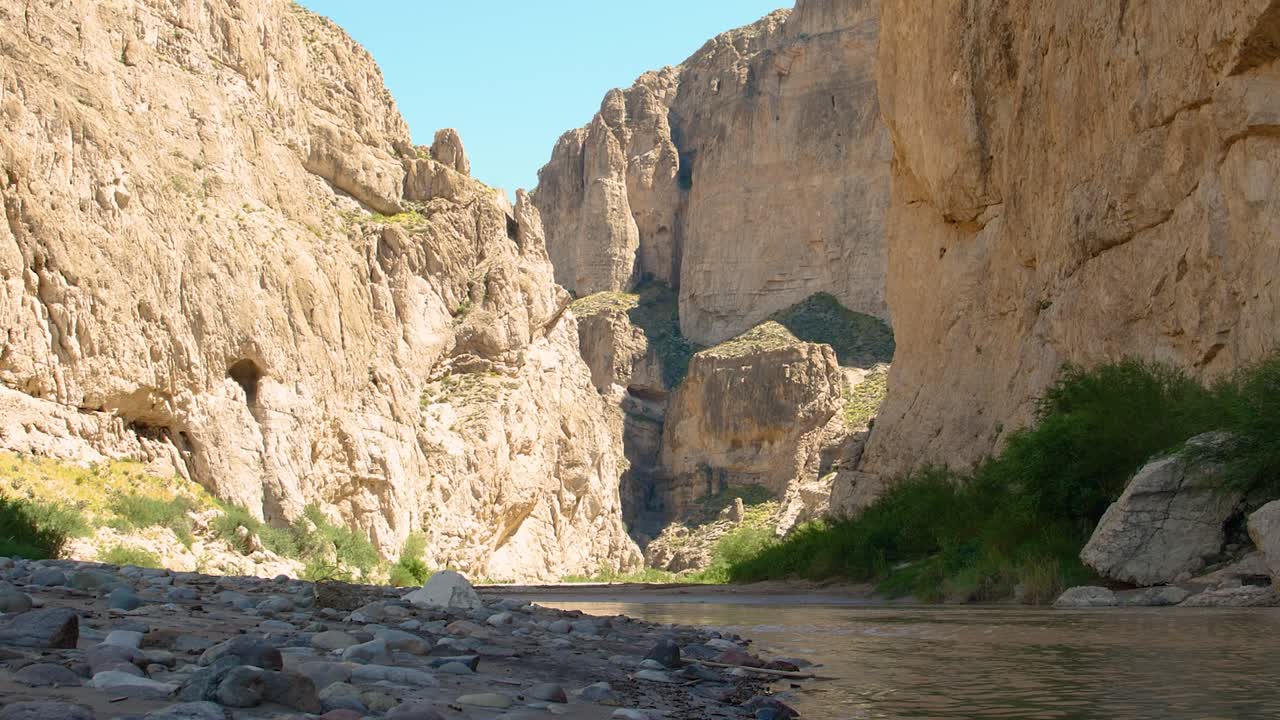 Big Bend National Park - Rio Grande 4K: Slow zoom from the river’s surface shows flowing water, pebbles on the U.S. side, and towering rock mountains on Mexico's side, marking the natural border.