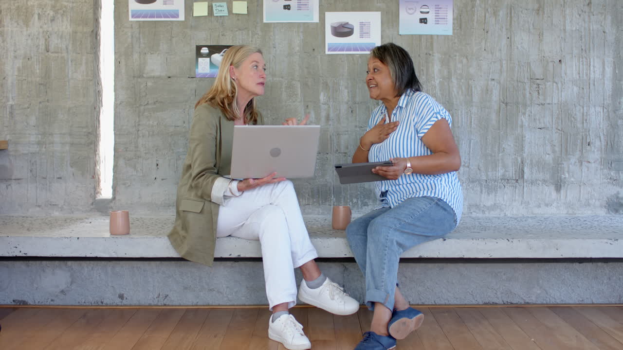 Project ideas, multiracial female friends using laptop and tablet while sitting, in office