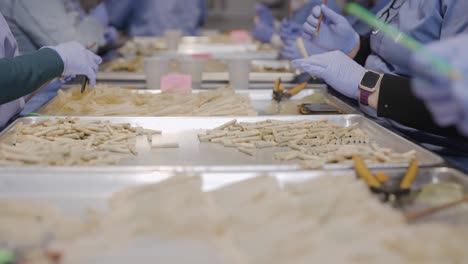 Slow-motion-shot-of-Workers-in-blue-gloves-trim-and-filling-up-Marijuana-Joints-in-Cannabis-production-factory