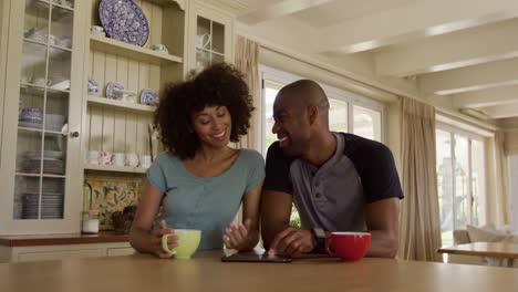 happy mixed race couple drinking coffee in their kitchen