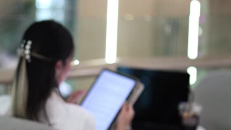 mujer enfocada interactuando con una tableta digital en el interior